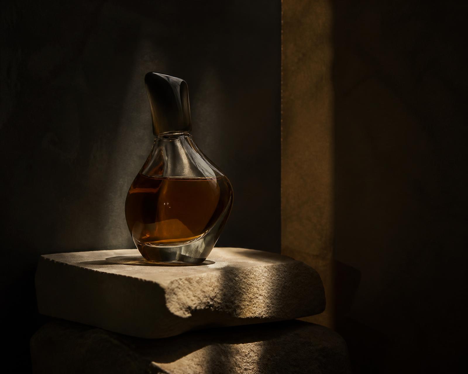 Oxblood and crystal niche fragrance bottles in architectural shadow